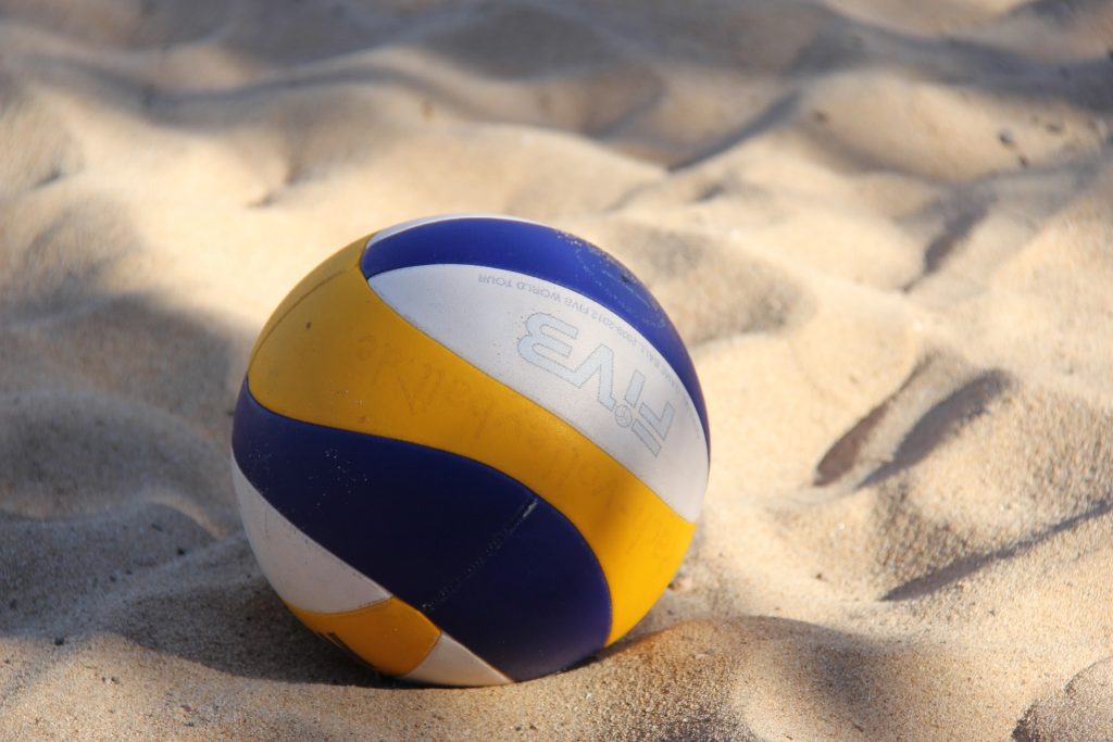 Beach volleyball resting on sand.