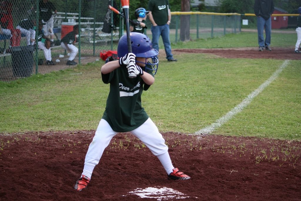 A little league player hitting a pitch.